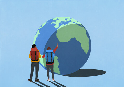 Backpackers pointing and looking up at large globe with shadow

