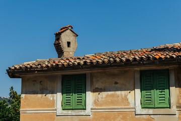 Part of an old Croatian house with a chimney on the roof against the blue sky on a sunny day