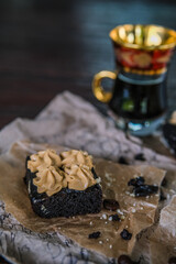 Fototapeta na wymiar Cup of coffee with chocolate brownies with cream and coffee beans on rustic recipe papers