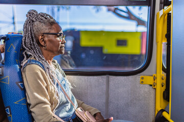 Senior woman with afro hairstyle sitting in bus. Profile.