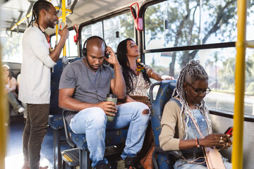 Passageiros multirraciais dentro do onibus em trajeto urbano.