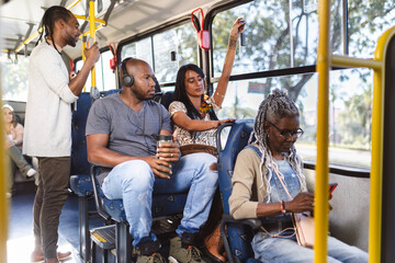 Multiracial passengers inside the bus on an urban route. - obrazy, fototapety, plakaty