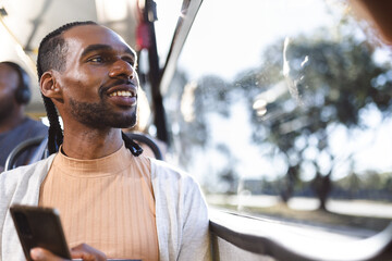 Homem negro, sorrindo, olhando pela janela do onibus.