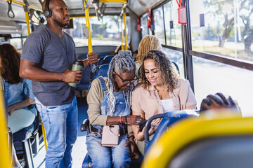 Two women looking at a smartphone while seated together on a city bus © Nexa