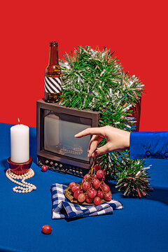 Crop hand picking grape near vintage TV