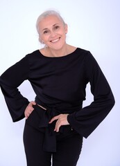 Aged mature woman in black suit on white background with smooth healthy skin face. Beautiful aging mature woman with blonde hair and happy smiling touching face. 