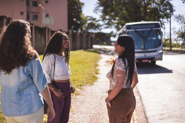 Grupo multiracial de mulheres conversando no ponto de onibus. - obrazy, fototapety, plakaty