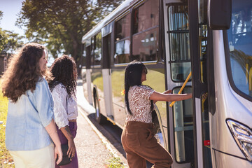 Multiracial group of women getting on the bus. - obrazy, fototapety, plakaty