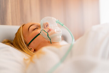 Close-up shot of a young girl lying in intensive care in an oxygen mask in hospital to maintain the...