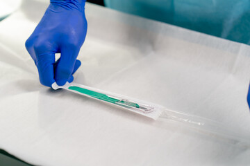Close-up shot of a surgeon's hands in gloves holding disposable sealed scalpel before surgery