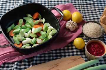turkish-style braised leeks food cooken in olive oil, fresh vegetables cut process with all ingredients on kitchen textile background, authentic look