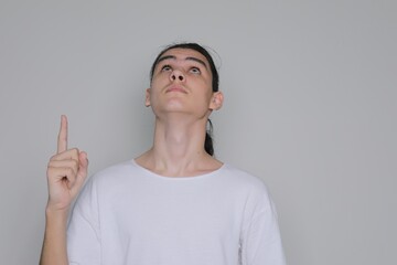 Young man showing index finger up gesture. Teenager looks at empty space above text