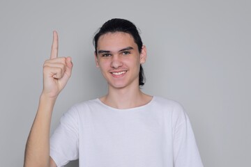 Young man, teenager shows index finger up and smiles