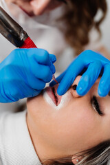 Professional permanent make up procedure. Tattoo lips makeup treatment in modern beauty salon.