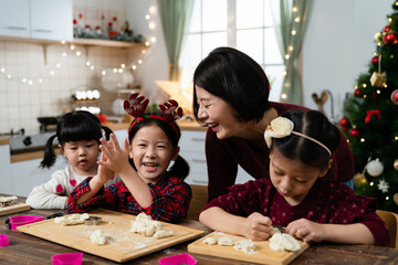 happy asian family smiling and feeling joy while preparing the dough for baking Christmas cookies together in the kitchen at home