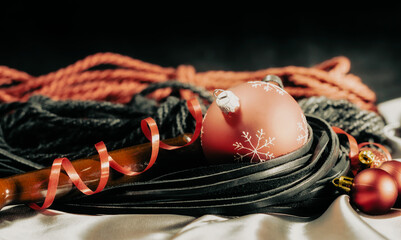 bdsm still life leather whip and christmas balls on silver fabric close up