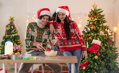 Young adult couple celebrating xmas Christmas thanksgiving in dining room kneading cake dough happy together. People enjoy celebrate Christmastime holiday with yummy good taste food and drink indoor.