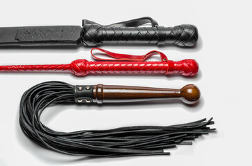 black and red three bdsm whips on a white background close up