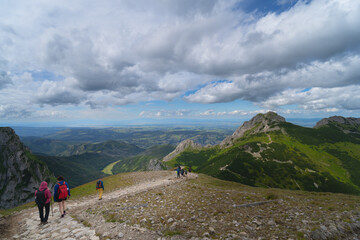 Obraz premium Travelers in the Polish Tatra Mountains go to the Giewont rock.