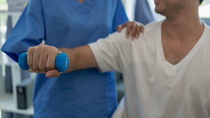 Physical therapist treating patient in bright office Modern day with male client, female physiotherapist helps man exercise muscles, arms, legs.