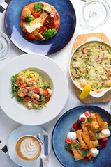 Tasty Restaurant Food Top View, Different Dishes on a Table, Pasta with Shrimp, Salmon Casserole, Chicken Fillet, Sweet Crepes and Coffee