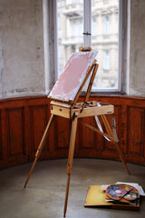 Artistic equipment in a artist studio: empty artist canvas on wooden easel and paint brushes 