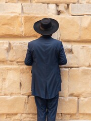 Jewish man standing in front of the wailing wall. praying.