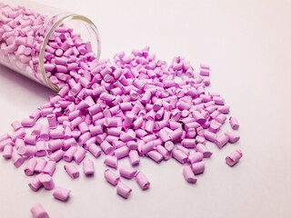 candy pink masterbatch granules with a glass tube isolated on a white background, this polymer is a...
