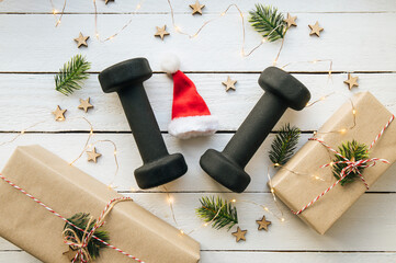 Healthy lifestyle during Christmas feasting period concept. Black dumbbells with Christmas...