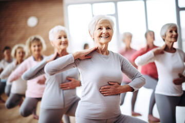 Group of active elderly people perform yoga together at a retreat center to improve their physical condition and well-being. Socialize with each other, active aging concept.