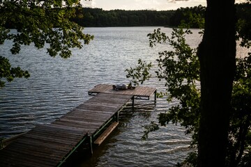 Tranquil scene of a small dock situated on the edge of a large lake surrounded by lush greenery.