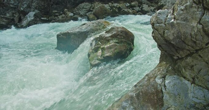 Powerful fast raging whitewater mountain river flow over rocks. Crystal clear glacier water stream. Rapids close-up.