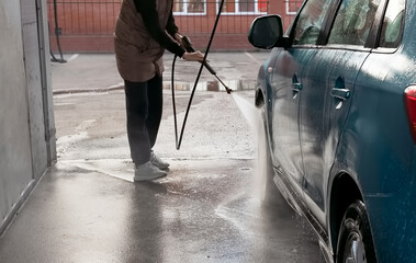 Manual car wash with pressurized water in car wash outside. Summer Car Washing. Cleaning Car Using High Pressure Water. Washing with soap. Close up concept.