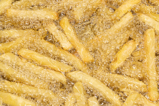 Delicious French Fries Frying on Food Background - Crispy and Golden Fast Food Snack