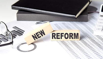 NEW REFORM - text on a wooden block with chart and notebook