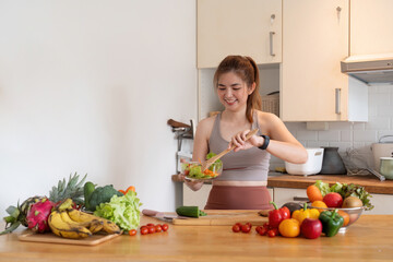 Young woman standing in the kitchen making a salad for health