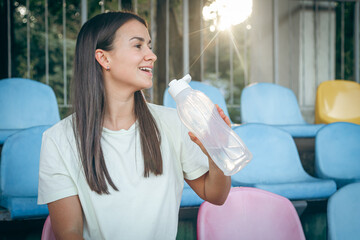A young woman with a bottle of water after training at the stadium.