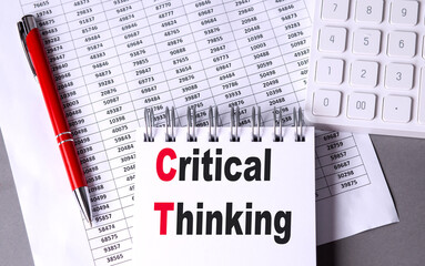 CRITICAL THINKING text on notebook with pen, calculator and chart on grey background