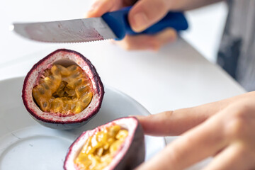 A woman cuts a passion fruit into two halves.