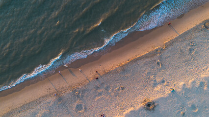 Beautiful flight in summer over the beach in Katwijk aan Zee. People are resting near the sea. Houses for tourists. Beach umbrellas, rides, people swimming in the sea. Beach in Netherland. North Sea. - 675338560