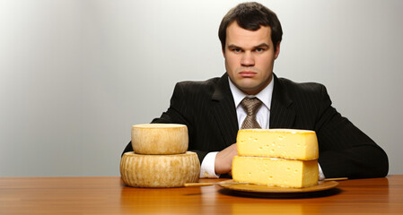 Hombre crítico serio mirando al frente con dos platos con queso