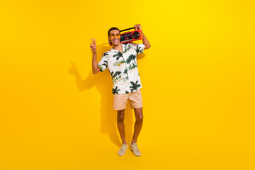 Full length photo of nice young male cool show v-sign tape recorder dressed stylish palms print garment isolated on yellow color background