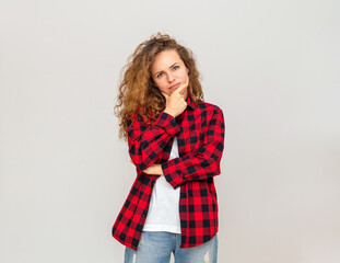 Female person thinking touching her chin with her hand in front of white backdrop. Body language and gesturing of thinking over.