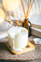 Cozy winter composition with a candle, incense sticks and bokeh lights.