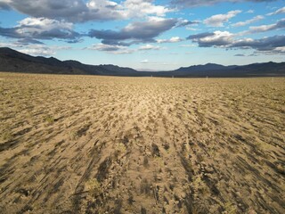Barren landscape featuring a dirt-covered terrain, with distant mountains in the background.