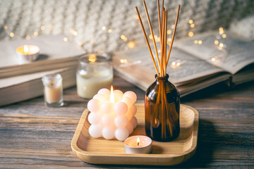 Winter spa composition with incense sticks, candles and bokeh lights.