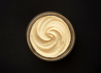 Glass bowl of fruit yogurt on black background, top view