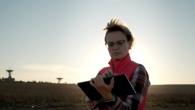 Woman operator equipment tablet pc controls solar radio telescope antennas.