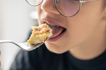 A girl eats a cheesecake, close-up of her mouth.