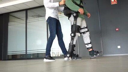 Mechanical exoskeleton, physiotherapist walking with unrecognizable disabled person with robotic skeleton, physiotherapy in a modern hospital: